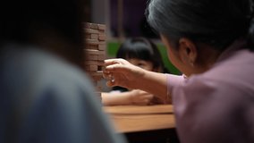 Asian happy family of little daughter play toy wooden block in home. Grandparents and young woman loving couple parent having fun play stack tower wood block game at night in living room. - Powered by Shutterstock - Get 15% off with code: PIKWIZARD15