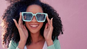Black woman with sunglasses smile, play with hair and laugh against pink backdrop in sunshine. Model girl with curly afro hair, happy with blue fashion glasses against color wall or background - Powered by Shutterstock - Get 15% off with code: PIKWIZARD15