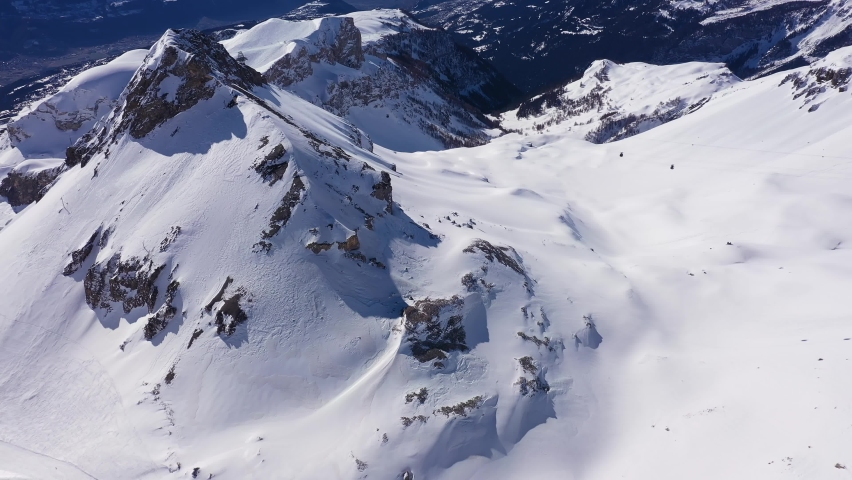 Crans-Montana, Switzerland: Aerial drone footage of the Plaine Morte glacier above the Rhone valley in the swiss alps in Canton Valais on a sunny winter day with a tilt up revealing motion