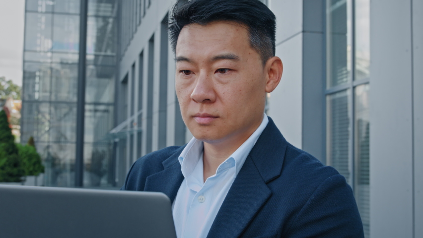 Close up Asian 40s middle-aged businessman entrepreneur employer man worker manager boss designer financial analyst working with computer typing laptop remote job online web project in city outdoors | Shutterstock HD Video #1094657229