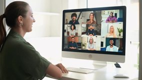 View above shoulder on a computer screen with a multiracial team. Female freelncer employee has remote meeting with diverse employees, virtual conference, webinar via video call on computer