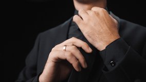 A man in a black suit tightens tie, close-up. - Powered by Shutterstock - Get 15% off with code: PIKWIZARD15