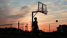 4k video Silhouettes of basketball players at the beautiful sunset. Amazing cinematic sport shoot. Two male playing street ball outside. - Powered by Shutterstock - Get 15% off with code: PIKWIZARD15