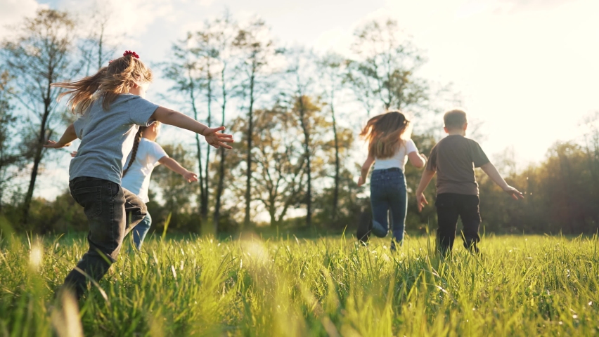 Children play in spring vacation park.Active happy group of kid run with a dog on grass in field in summer.Family in nature with pet.Child on play.Happy family concept.School in garden with dog Royalty-Free Stock Footage #1094662537