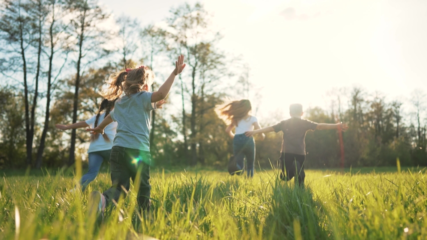Children play in spring vacation park.Active happy group of kid run with a dog on grass in field in summer.Family in nature with pet.Child on play.Happy family concept.School in garden with dog