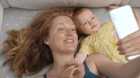 Young mother and her newborn baby making a selfie or video call in a bed. Technology, family, parenthood. Top view - Powered by Shutterstock - Get 15% off with code: PIKWIZARD15