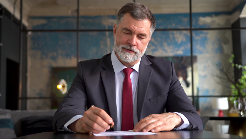 Senior business man signs a approval document in the office. Mature gray successful banker or lawyer businessman reading and signing business partnership contract. | Shutterstock HD Video #1094666337