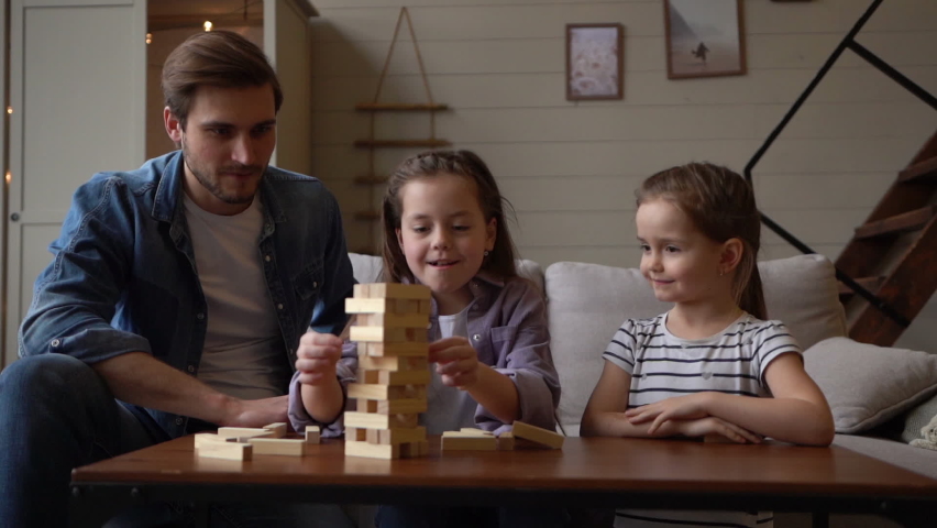 Small pretty girls plays a tiny jenga with father, jenga tower falls apart, all have great time together, happy childhood concept