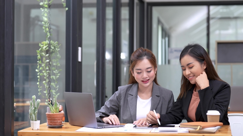 Two diverse business women discussing financial market data using laptop and digital tablet. Financial advisor broker manager consulting investor client about digital investment at office meeting | Shutterstock HD Video #1094666715