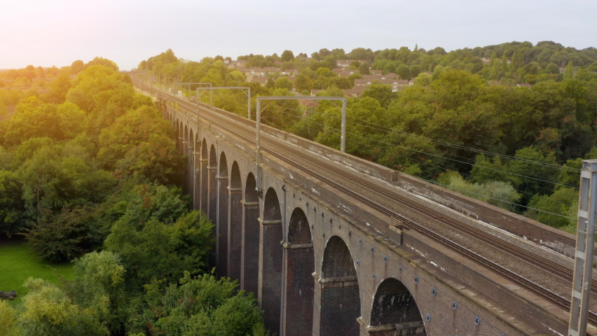 Aerial view of a moving train along the Viaduct. high-speed train passes an arched railway bridge. Aerial drone footage of a train crossing the famous  viaduc. England. UK. London.  Royalty-Free Stock Footage #1094669305