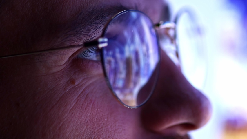 Close up view of man's eyes in glasses looking at pc screen with computer reflection at eyewear. Using internet, working online, following for stock exchange. Concept of technology, AI, business | Shutterstock HD Video #1094669335
