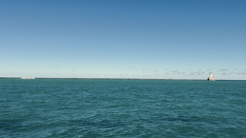 Lake Michigan landscape and a small lighthouse on the horizon. Big lake and landscape in the day. Cloudless blue sky. The static shot is shot from the hands.