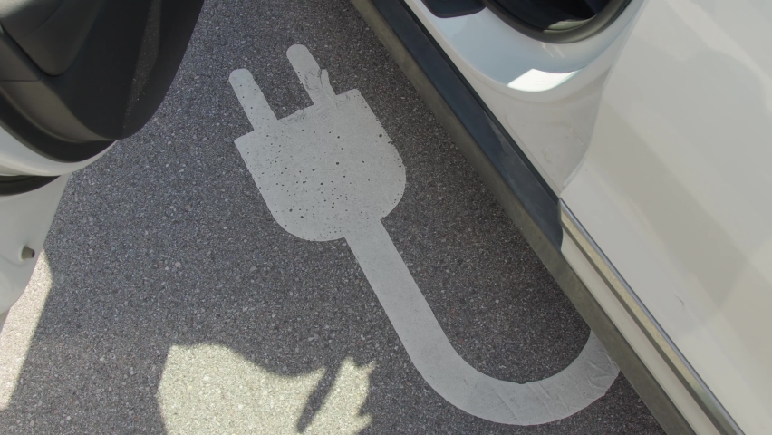 electric charging sign on asphalt and car with open door