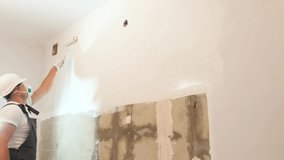 Professional builder with roller painting the wall while working. Modern repair
