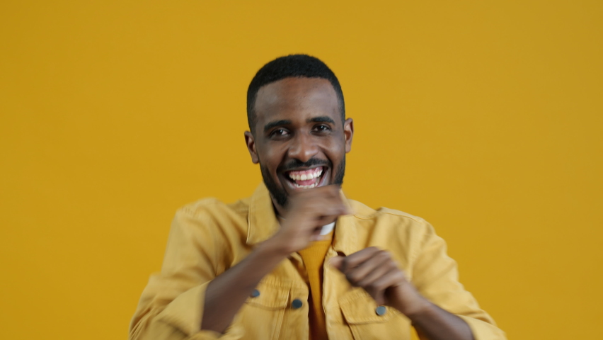 Portrait of good-looking Afican American guy dancing on yellow background smiling having fun alone. People and active lifestyle concept. | Shutterstock HD Video #1094684099