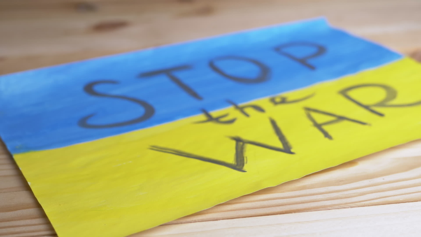 Hand Puts a Biometric Passport of Ukraine on a Background of Ukrainian Flag. Children