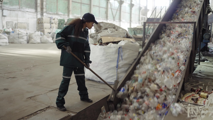 A young African-American woman checks a conveyor belt at a recycling plant. Pollution control | Shutterstock HD Video #1094690223
