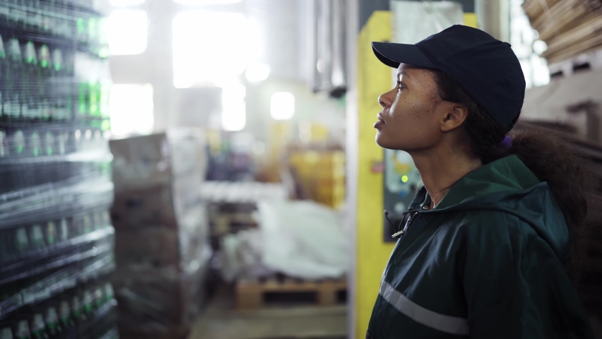 An African-American woman in a special green uniform monitors the process of packaging raw materials at a waste processing plant. Processing of raw materials, recycling. Pollution control | Shutterstock HD Video #1094690227