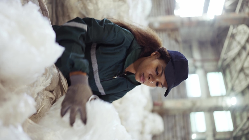 An African-American woman in a special uniform sorts polyethylene at a waste recycling plant. Processing of raw materials, recycling. Pollution control | Shutterstock HD Video #1094690229