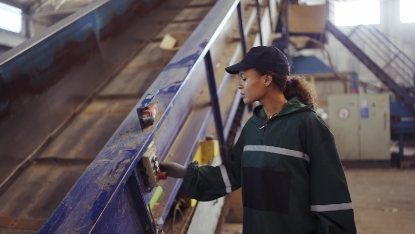 Young african american woman checking conveyor belt with push buttons at waste recycling plant. Pollution control | Shutterstock HD Video #1094690231
