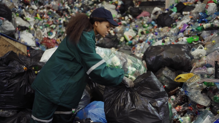 African American woman sorting garbage bags at a recycling plant. Pollution control | Shutterstock HD Video #1094690241