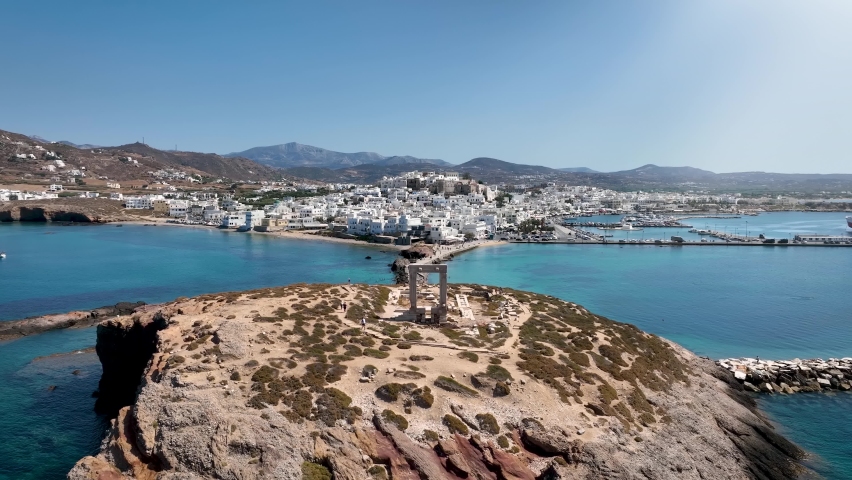 Aerial view of the famous Portara marble gate with the white houses of the city of Naxos island, Cyclades, Greece, during a sunny summer day Royalty-Free Stock Footage #1094694943