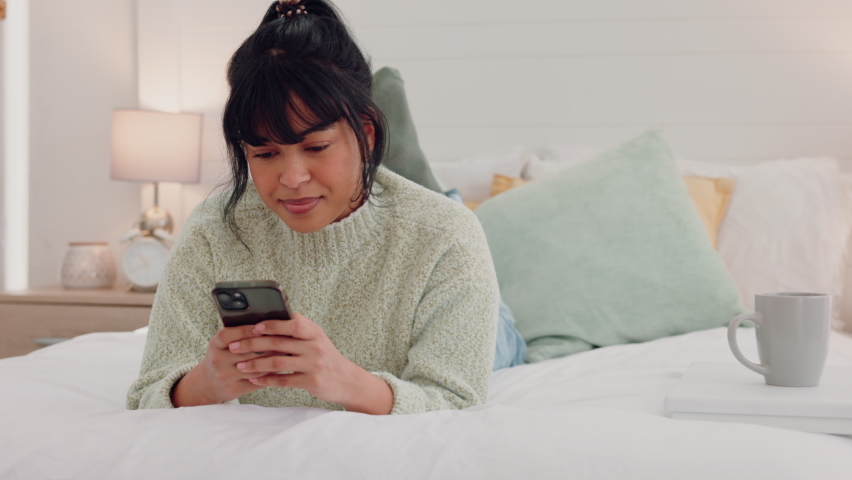 Bed, coffee and woman texting on a phone, relax with social media and online conversation in a bedroom. Rest, streaming and internet entertainment with black female enjoying a resting day in her home | Shutterstock HD Video #1094697983