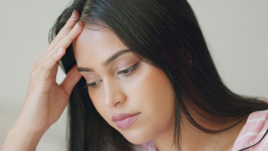 Stress, headache and burnout with a woman suffering with anxiety, worry or a migraine while rubbing her head with her hand. Mental health, sad and frustrated with a young female feeling depressed | Shutterstock HD Video #1094698185