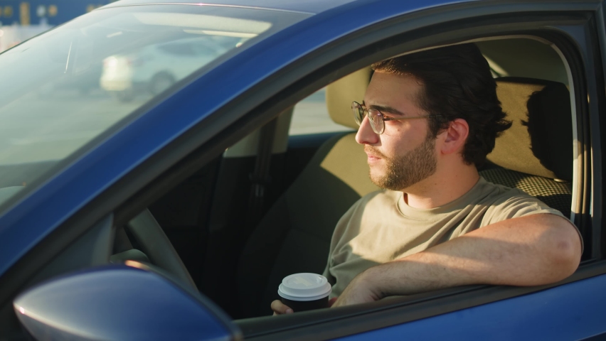 Young man driver drinking coffee close-up. Car sharing concept, vehicle and transport. Spanish happy guy driving, sitting in blue car and drinking coffee. Traveling by automobile. Royalty-Free Stock Footage #1094701865