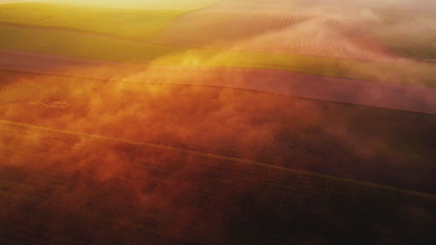 Thick fog covering colorful farm fields with orange glaze from rising sun. Morning landscape of Roztocze Poland. Birdseye view. Horizontal shot. High quality 4k footage