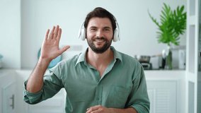 Attractive confident young dark-haired man wearing wireless headphones looking directly at camera, recording video, having video conference. Perfect promotional clip to insert into your laptop monitor - Powered by Shutterstock - Get 15% off with code: PIKWIZARD15