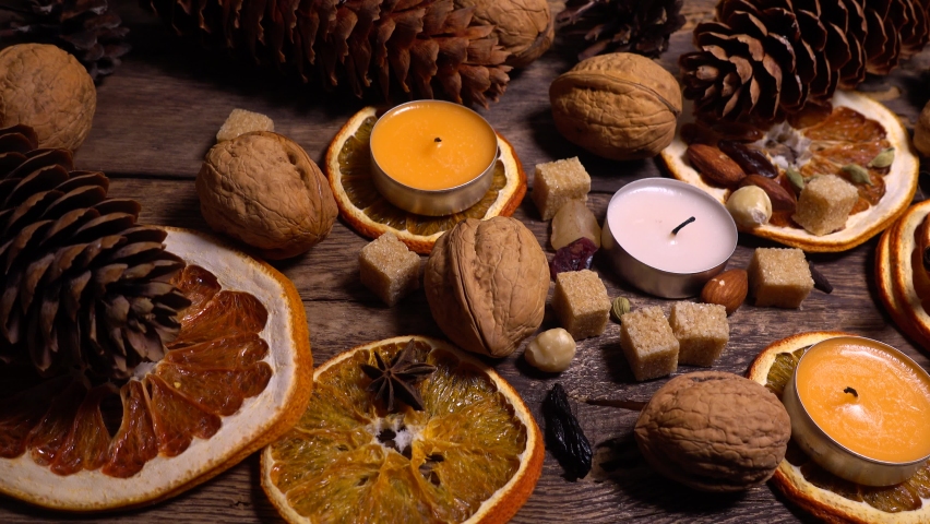 Natural composition in hygge style with candles, orange slices, fragrant spices, walnuts and pine cones on an old vintage wooden board background. - Powered by Shutterstock - Get 15% off with code: PIKWIZARD15