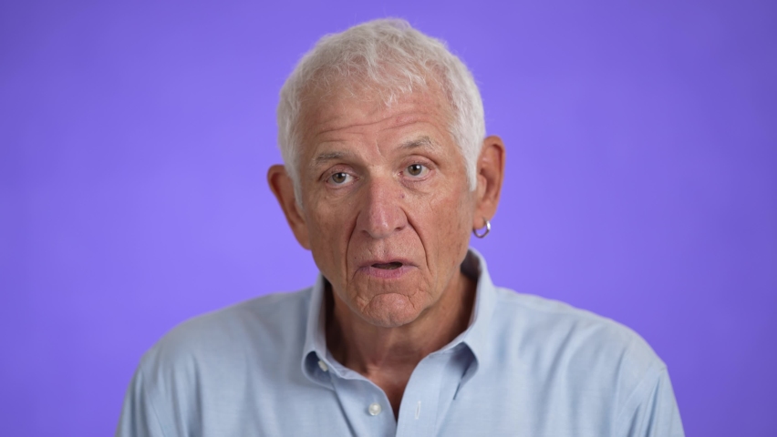 Handsome elderly man shaking head no, pensive mood, isolated on light purple background. Studio portrait. | Shutterstock HD Video #1094717797