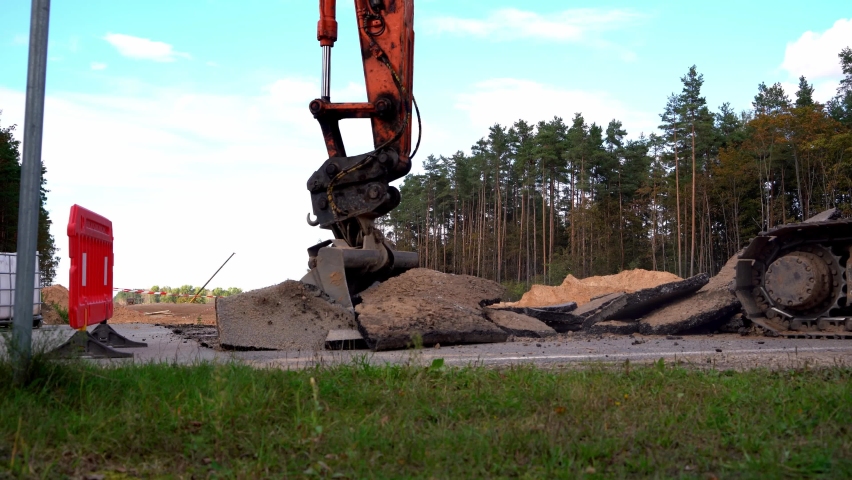 Excavator bucket breaks old asphalt. Construction site. Dismantling of old asphalt in a new highway at a construction site | Shutterstock HD Video #1094722071