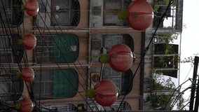 Vertical video - Red lanterns blow by wind and adorn a small alley in Chinatown Bangkok, Thailand.