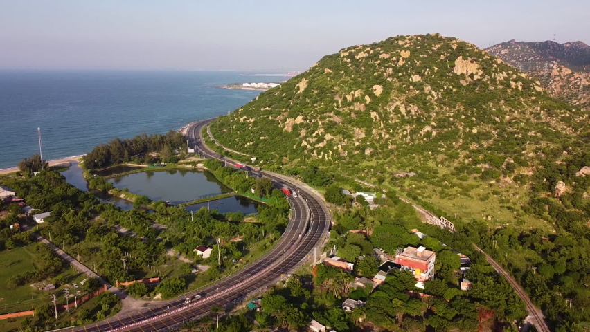 Backwards aerial view over a promontory next to main coastal road. Ca Na, Vietnam.