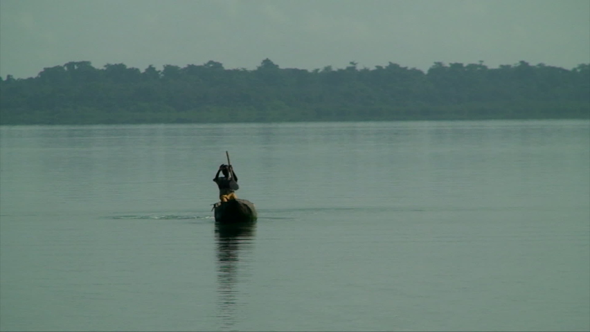 A young man paddling an artisanal canoe, built from the trunk of a large tree, on the São Domingos River