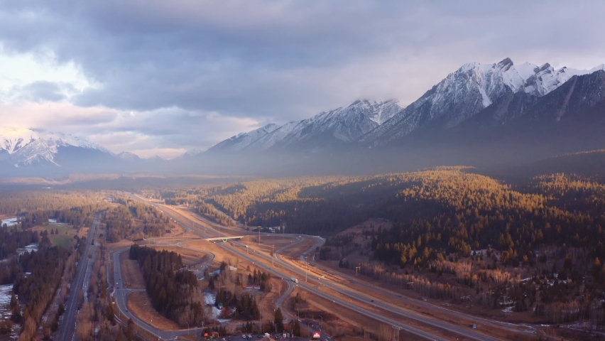 Canmore Alberta mountain range Canadian rockies surrounding highway and overpass aerial sunrise drone shot pan away. Royalty-Free Stock Footage #1094725665