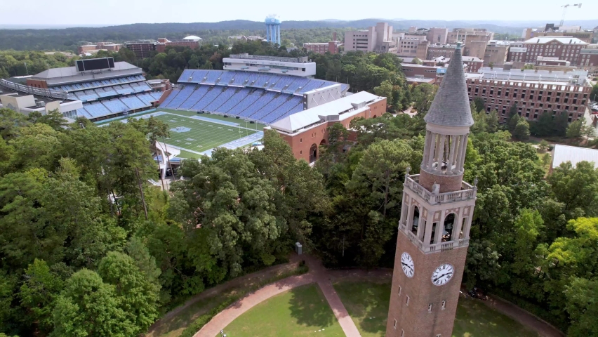 aerial orbit of the moorehead patterson clock tower with kenan memorial stadium in the background on the unc chapel hill campus