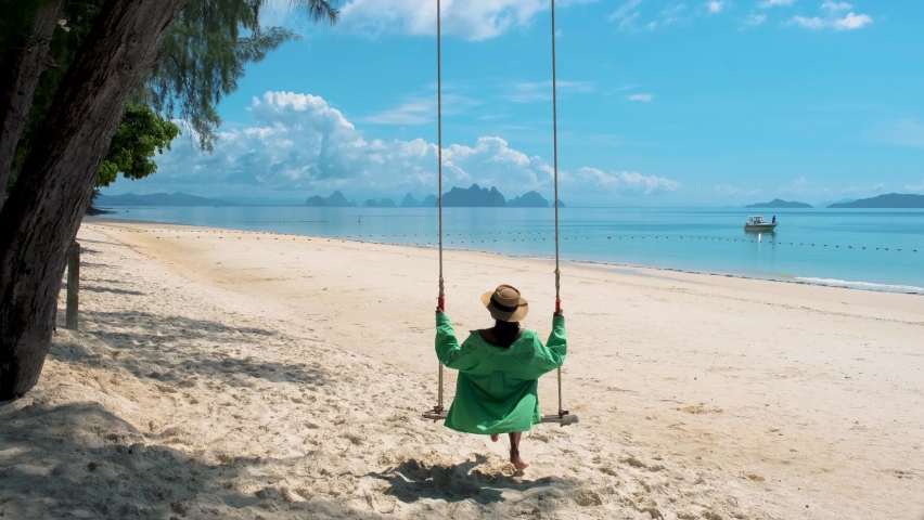 woman on the beach of the tropical Island Naka Island near Phuket Thailand, a woman on a swing on the beach in Thailand Royalty-Free Stock Footage #1094734487