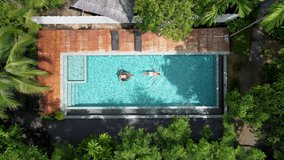 aerial drone view of swimming pool in the jungle of Krabi Thailand, aerial view with a drone above swimming pool in the jungle of Thailand. couple men and woman in pool from above - Powered by Shutterstock - Get 15% off with code: PIKWIZARD15