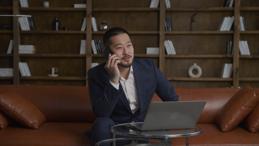 Asian businessman setting a deal during a call on his smart phone in loft office | Shutterstock HD Video #1094735619