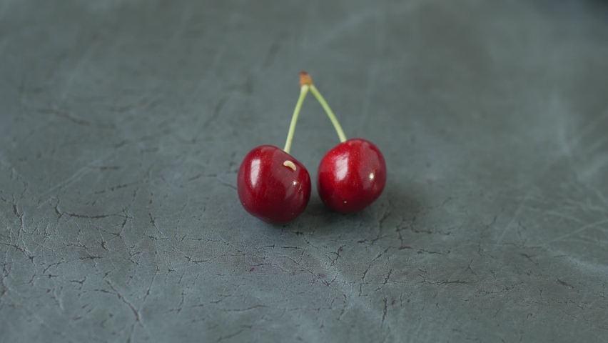 White worm crawls over ripe sweet cherries with green stalks on gray table. Hand of unrecognizable person removes the larva from fruit with metal tweezers. | Shutterstock HD Video #1094743305