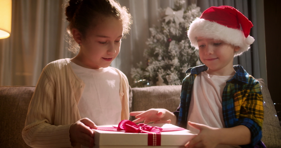 Happy cute children,delighted with surprise, opens box Christmas gifts and falls down with happiness in joy from his gift. Portrait beautiful little children,children opens box with surprise Christmas Royalty-Free Stock Footage #1094743927