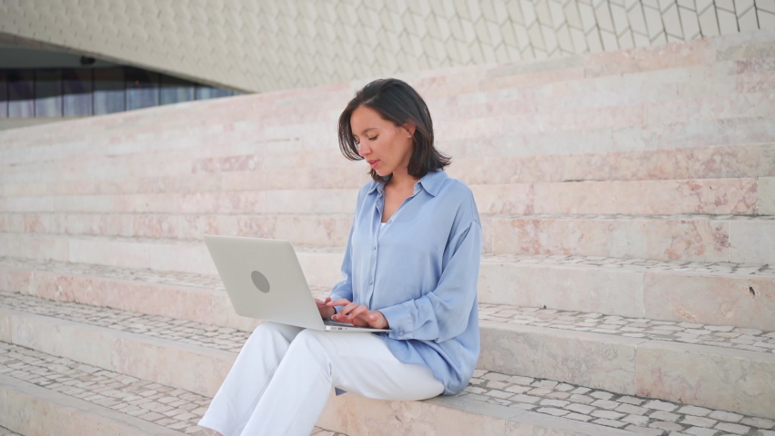 Businesswoman use laptop outdoor sitting stairs. Caucasian female business person 30 years typing laptop keyboard. Remote work freelancer concept. Freelance job its new normal | Shutterstock HD Video #1094748343
