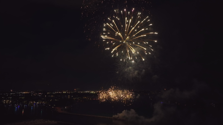 Aerial view of bright fireworks exploding with colorful lights over sea shore on US Independence day holiday
