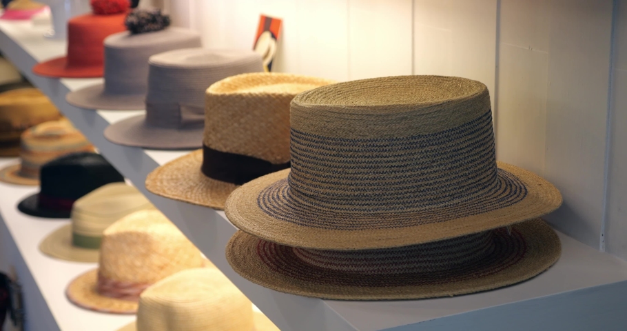 Steadicam shot: New seasonal collection of summer straw hats on shelves, display for sale in the headwear brand boutique. Headdress. Headgear. Clothing store showcase with variety of caps and hats | Shutterstock HD Video #1094752853