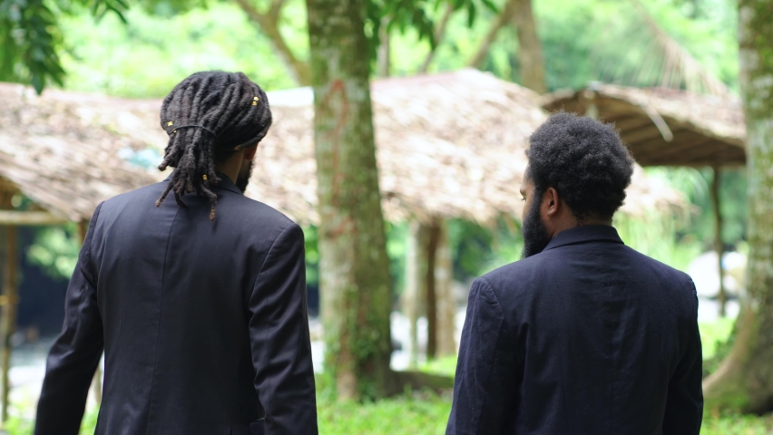 Footage From Two African Man in Suit With a Lot of Wrinkle Doing a Conversation While Taking From Their Back at a Forest in the Nature