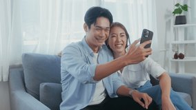 Young smiling asian couple holding smartphone and making video call at home - Powered by Shutterstock - Get 15% off with code: PIKWIZARD15