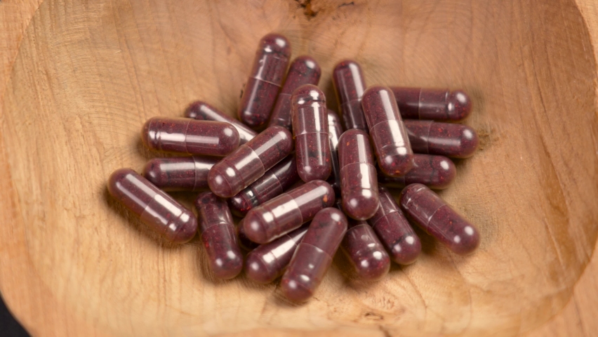 Purple capsules with blueberries in a rustic dish. Superfood supplement with bilberry extract powder. Rotation. Macro. Alternative medical support pills | Shutterstock HD Video #1094760935